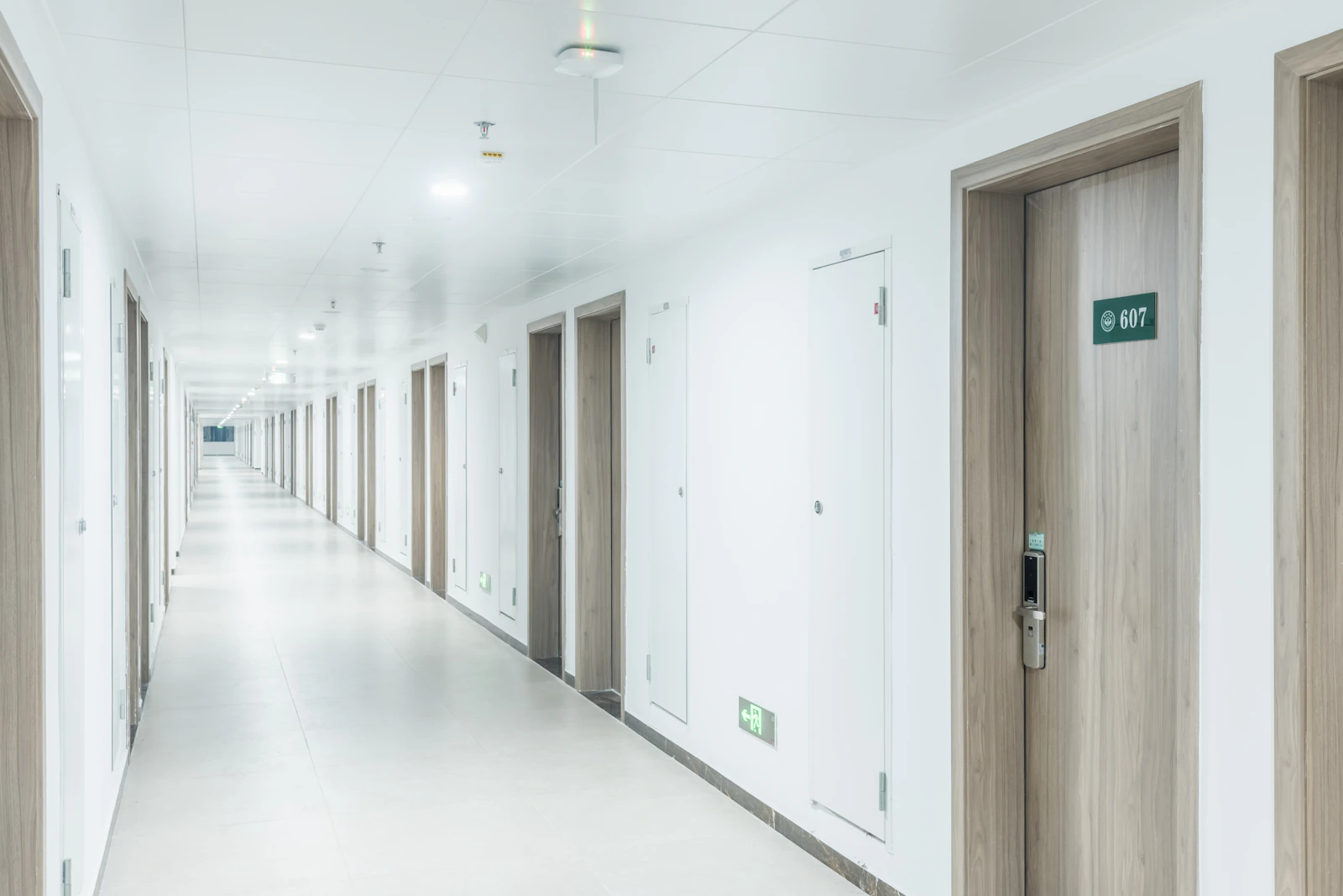 Long apartment building hallway with multiple doors leading to individual units