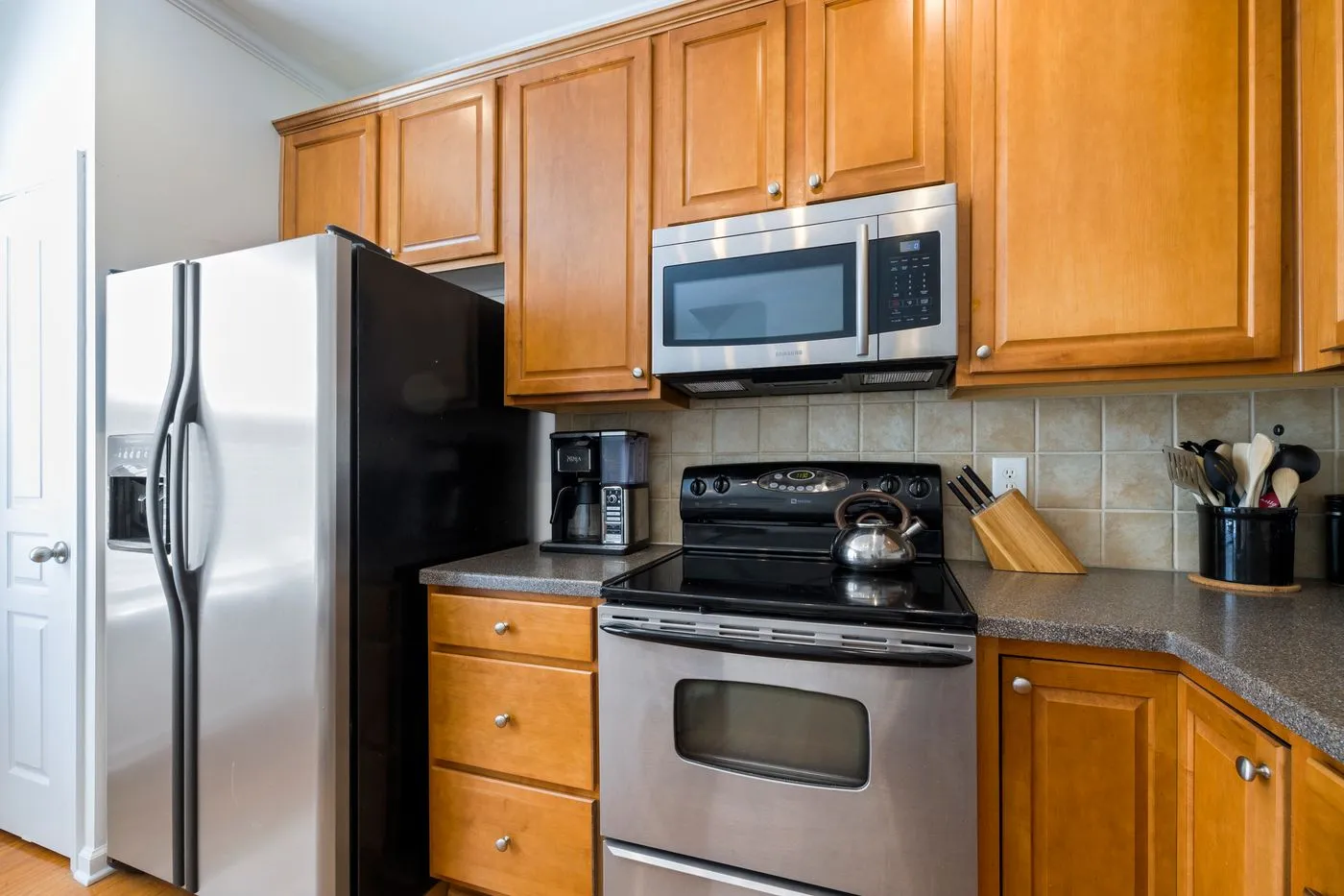 Kitchen fitted with a stainless steel side-by-side fridge, over-range microwave and gas cooker