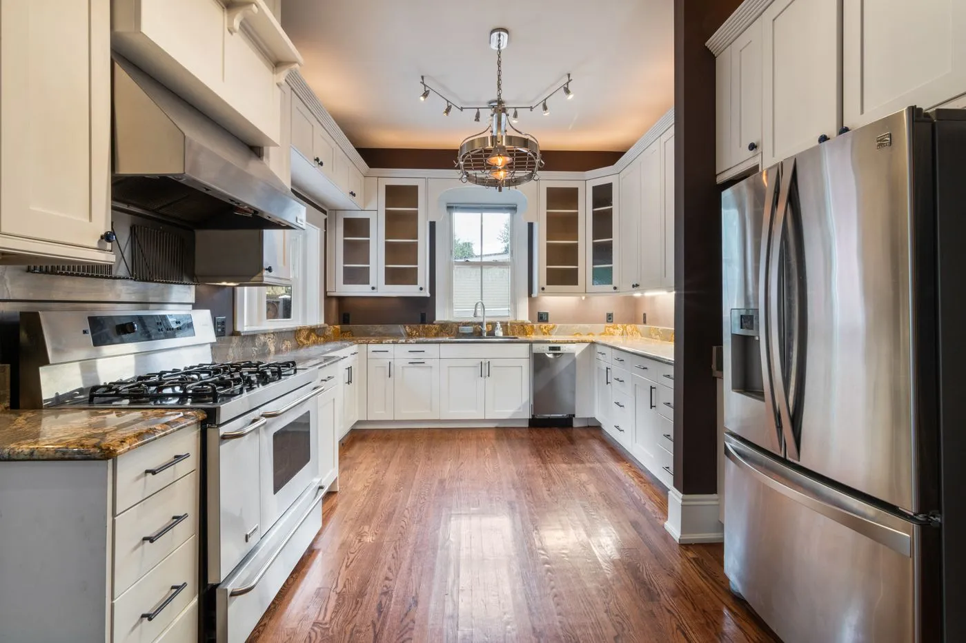 Fitted kitchen with a dishwasher built into a run of units beside a freestanding cooker and extractor hood