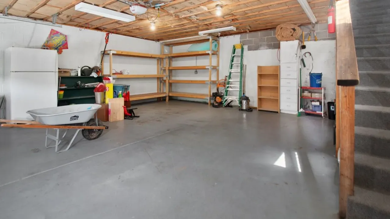 Cleared residential garage with swept concrete floor and wall shelving where stored bicycles and outdoor sports kit are kept