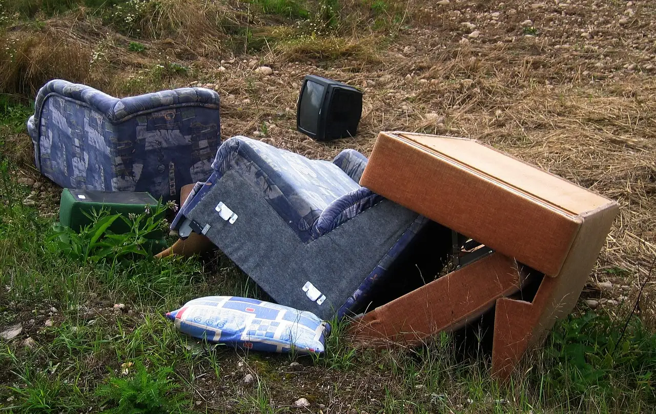 Blue patterned armchair broken into separate pieces on open ground, with the seat base, backrest, side panel and a loose cushion lying apart