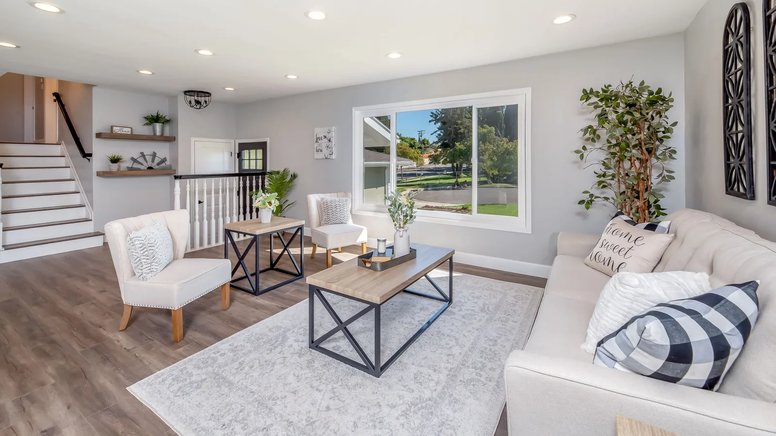 Bright living room with a large grey area rug covering the floor between a sofa, armchairs and a coffee table