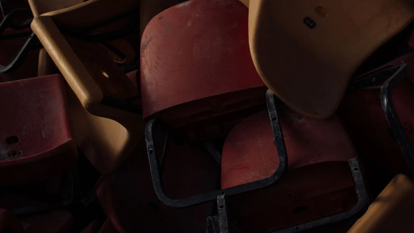 Pile of worn plastic stacking chair seats with metal frames jumbled together, showing cracked and faded surfaces