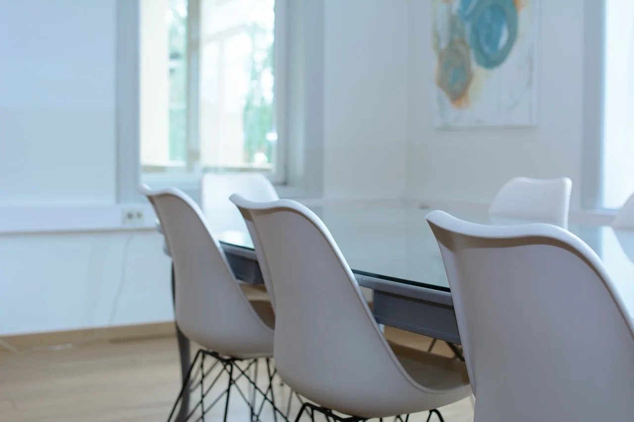 Glass-walled meeting room inside a commercial office with white conference chairs around a meeting table