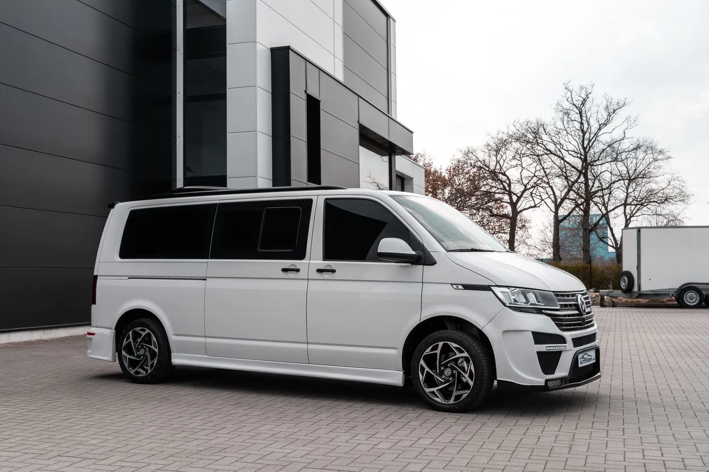 White van parked on paving outside a modern grey and white commercial building