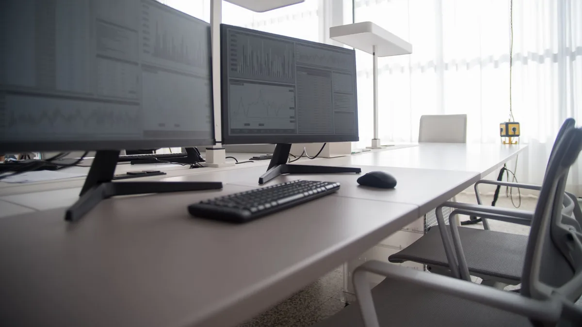 Row of office desktop computer monitors and workstations in a Dubai office cleared during computer removal