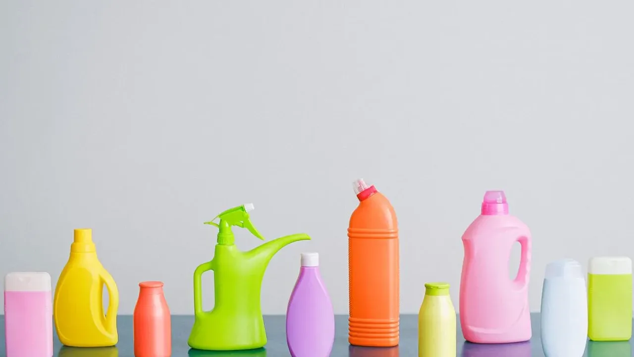 Row of brightly coloured plastic toiletry and cleaning bottles lined up along a grey counter against a pale wall