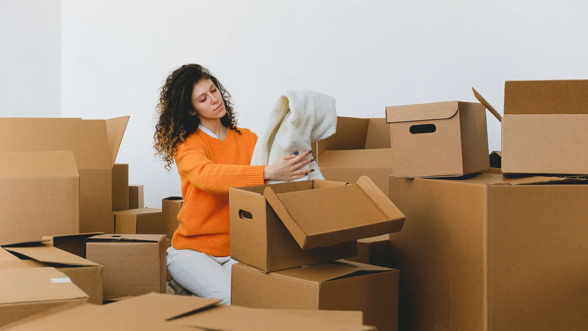Woman packing clothes into moving boxes in an apartment ahead of an end-of-tenancy move in Dubai