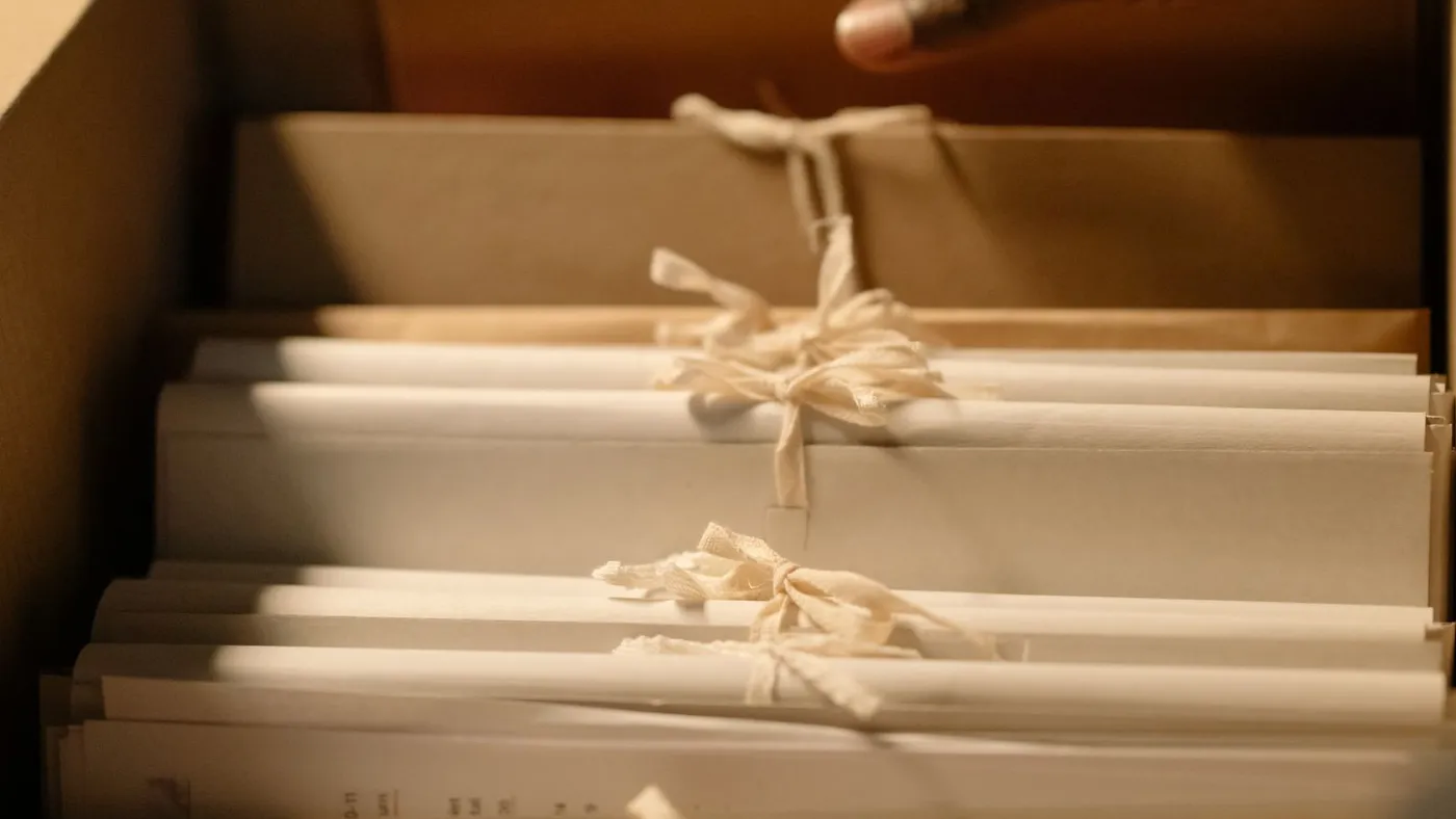 Close-up of cream paper document bundles tied with cloth ribbon standing upright in an open archive drawer
