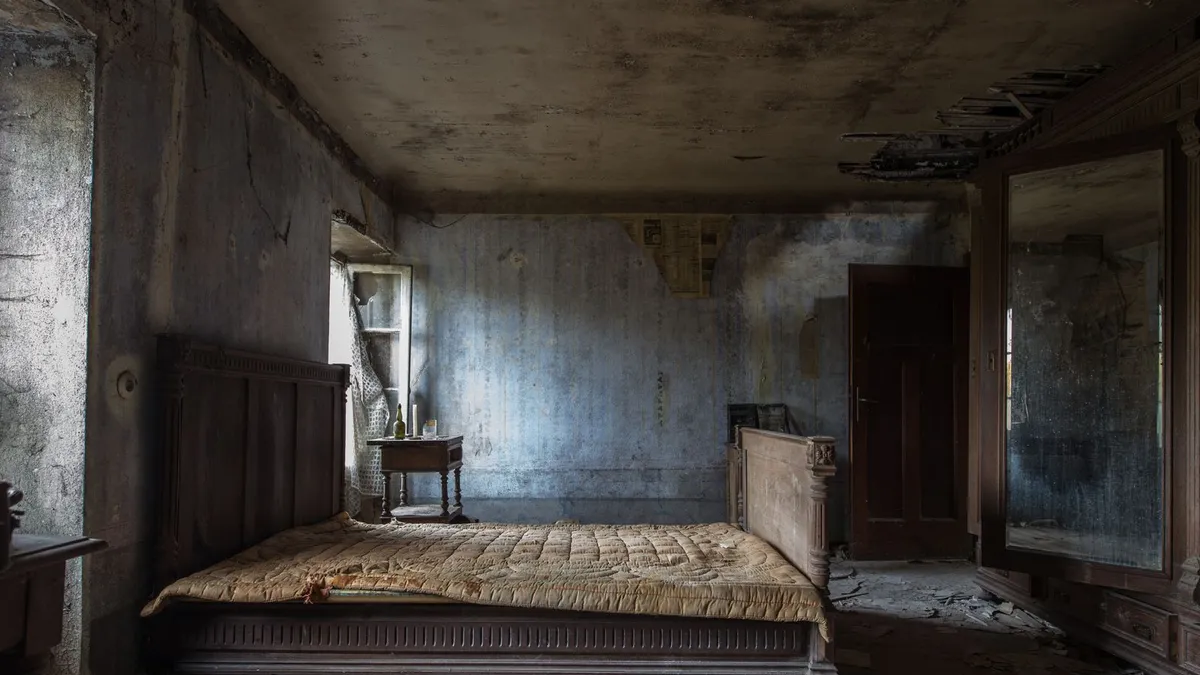 Old wooden bed frame, mattress and mirrored wardrobe in a cleared room, showing bed and wardrobe disposal in Dubai