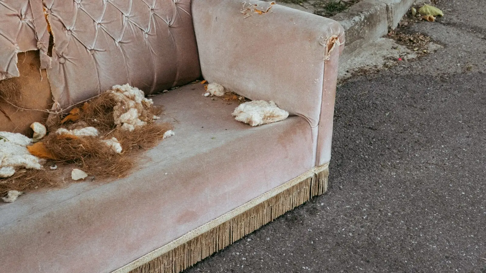 Worn-out pink velvet sofa dumped on a street kerb, showing why responsible furniture disposal in Dubai matters