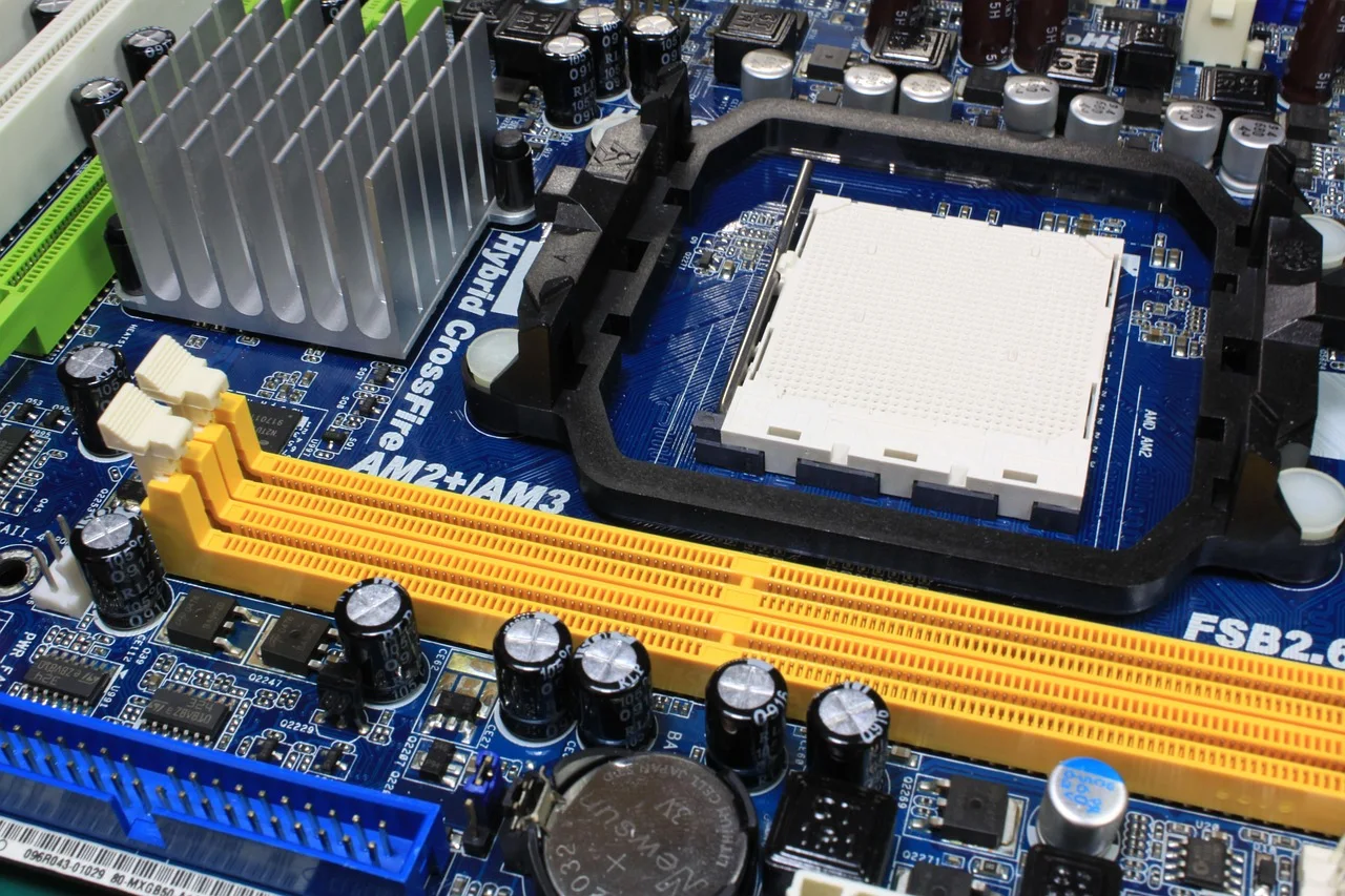Computer motherboard showing empty central processor socket, aluminum heatsink fins, and dual-channel RAM memory slots