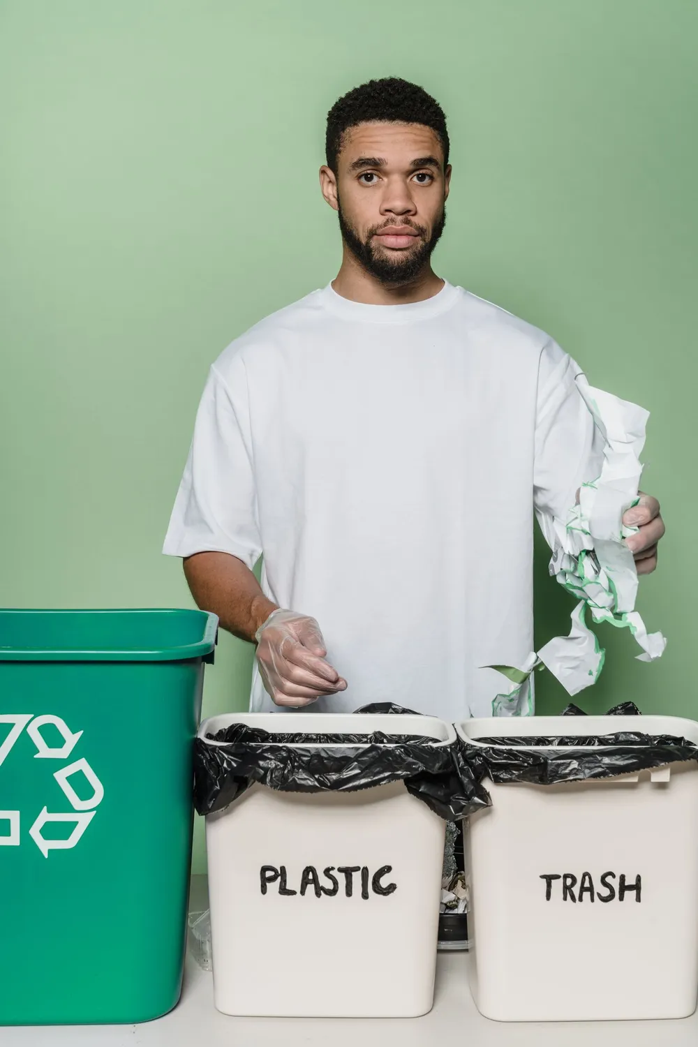 Worker separating general waste and recyclables into labelled bins during garbage collection in Dubai