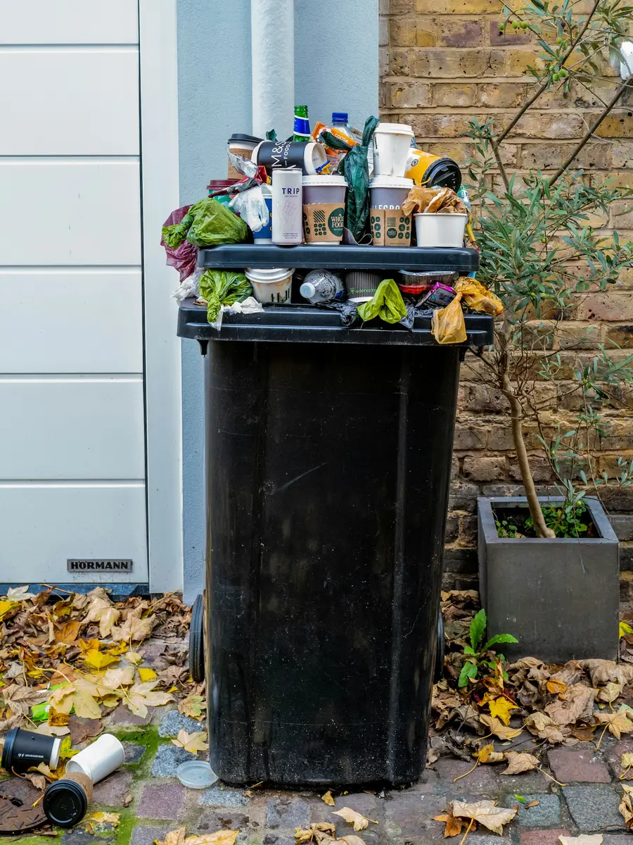 Overflowing household garbage bin outside a home in Dubai, showing why regular scheduled garbage collection is needed