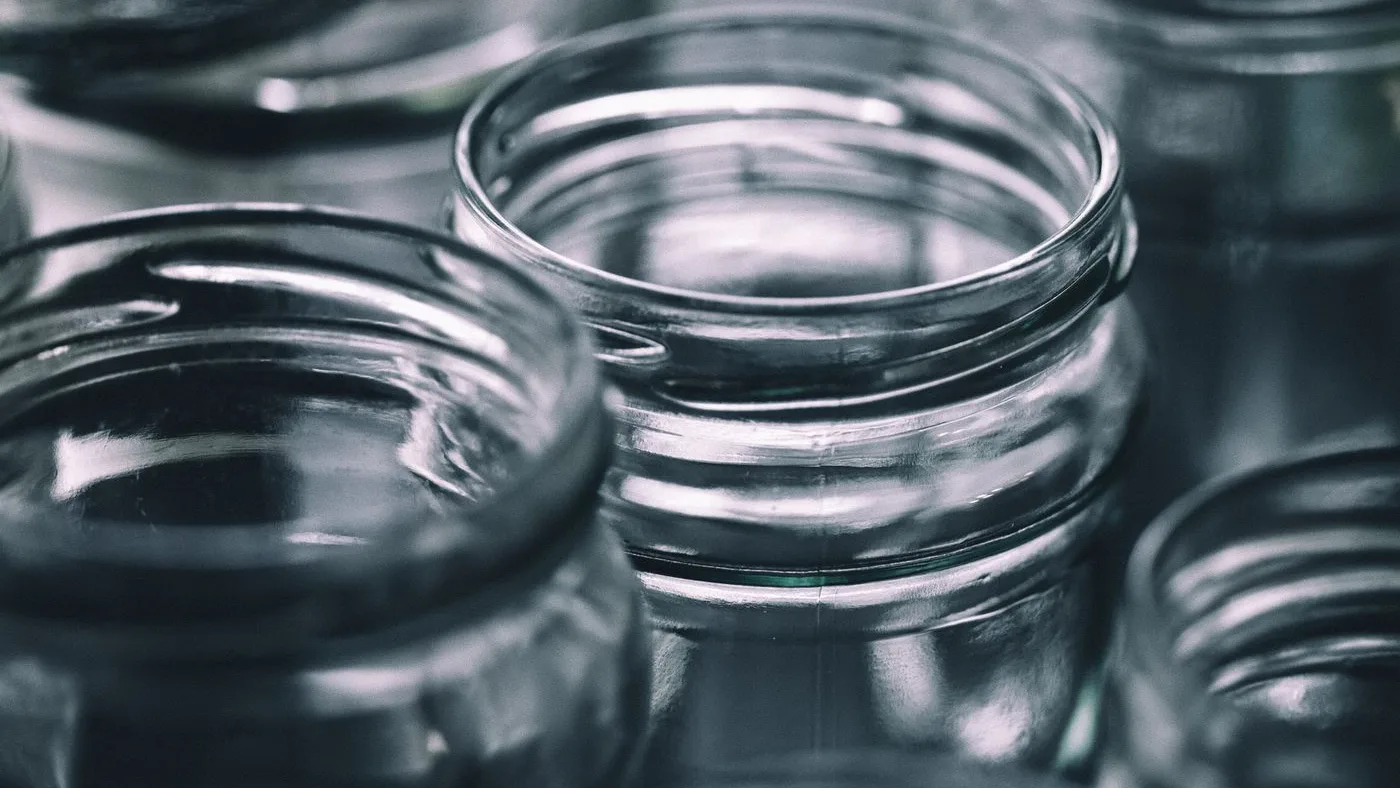 Close-up of empty clear glass jars with open screw-thread necks and their lids removed