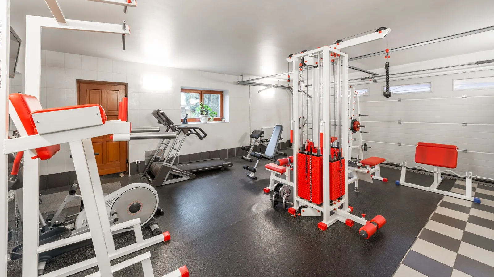 Home gym in a Dubai villa basement with a treadmill and weight equipment set up against a mirrored wall