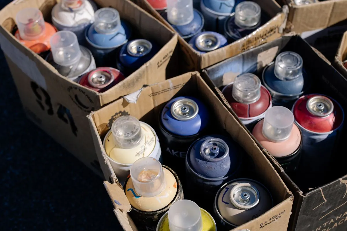 Cardboard boxes packed with used spray paint aerosol cans of mixed colours