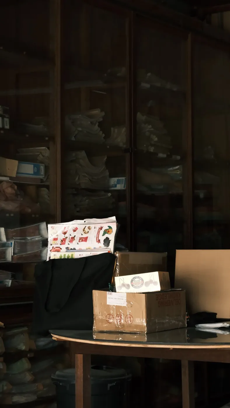 Dimly lit room lined with tightly packed shelves holding stacked boxes and household items floor to ceiling