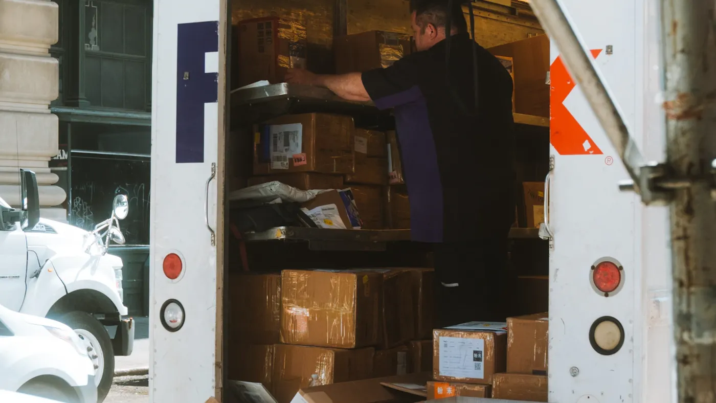 Man loading furniture and boxes into the back of a truck outside a home during a junk removal collection