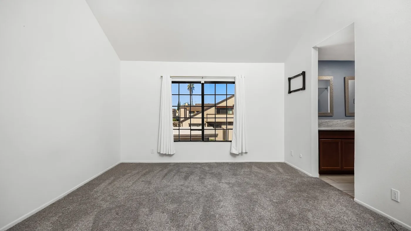 Empty living room with a large window and bare wooden flooring after a home clear-out