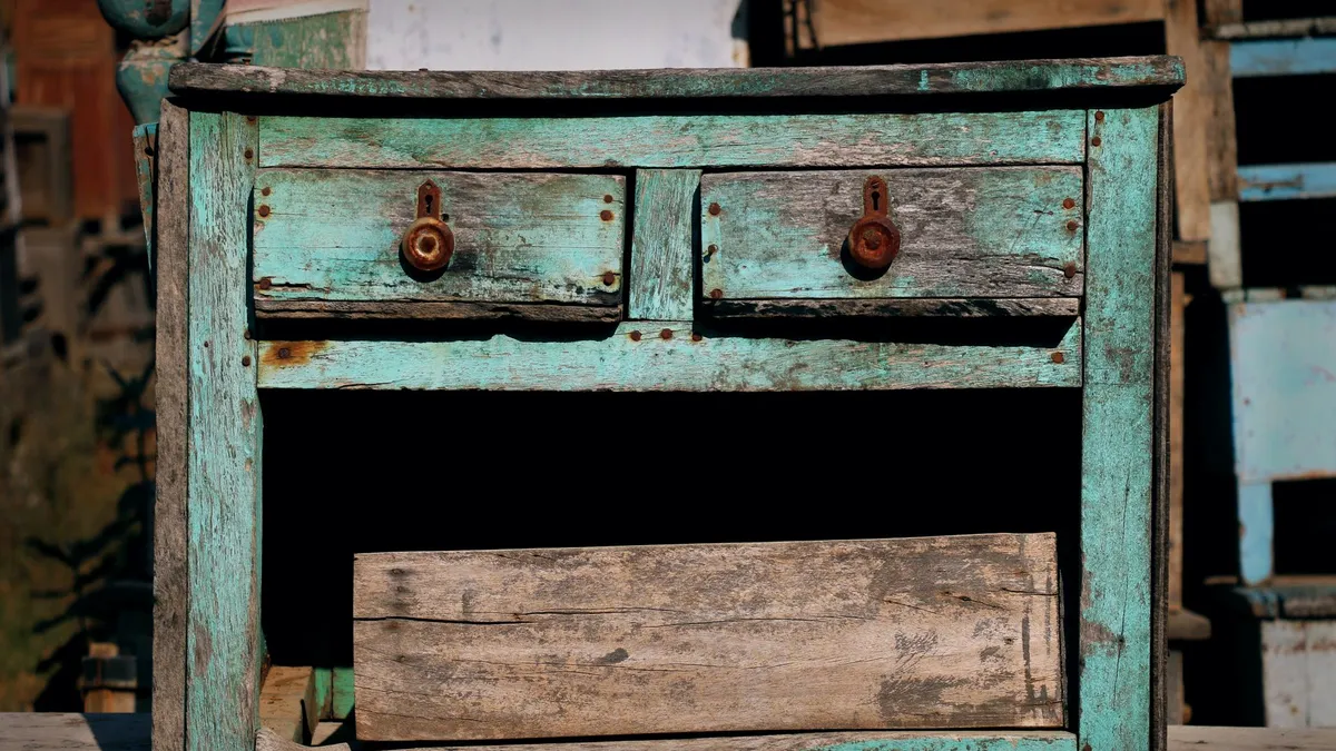 Old weathered wooden dresser with peeling paint and broken drawers, an example of furniture that is beyond repair in Dubai