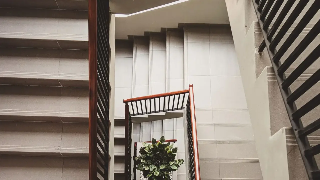 Tall apartment stairwell with several tight square landings, tiled steps and metal railings around a central opening