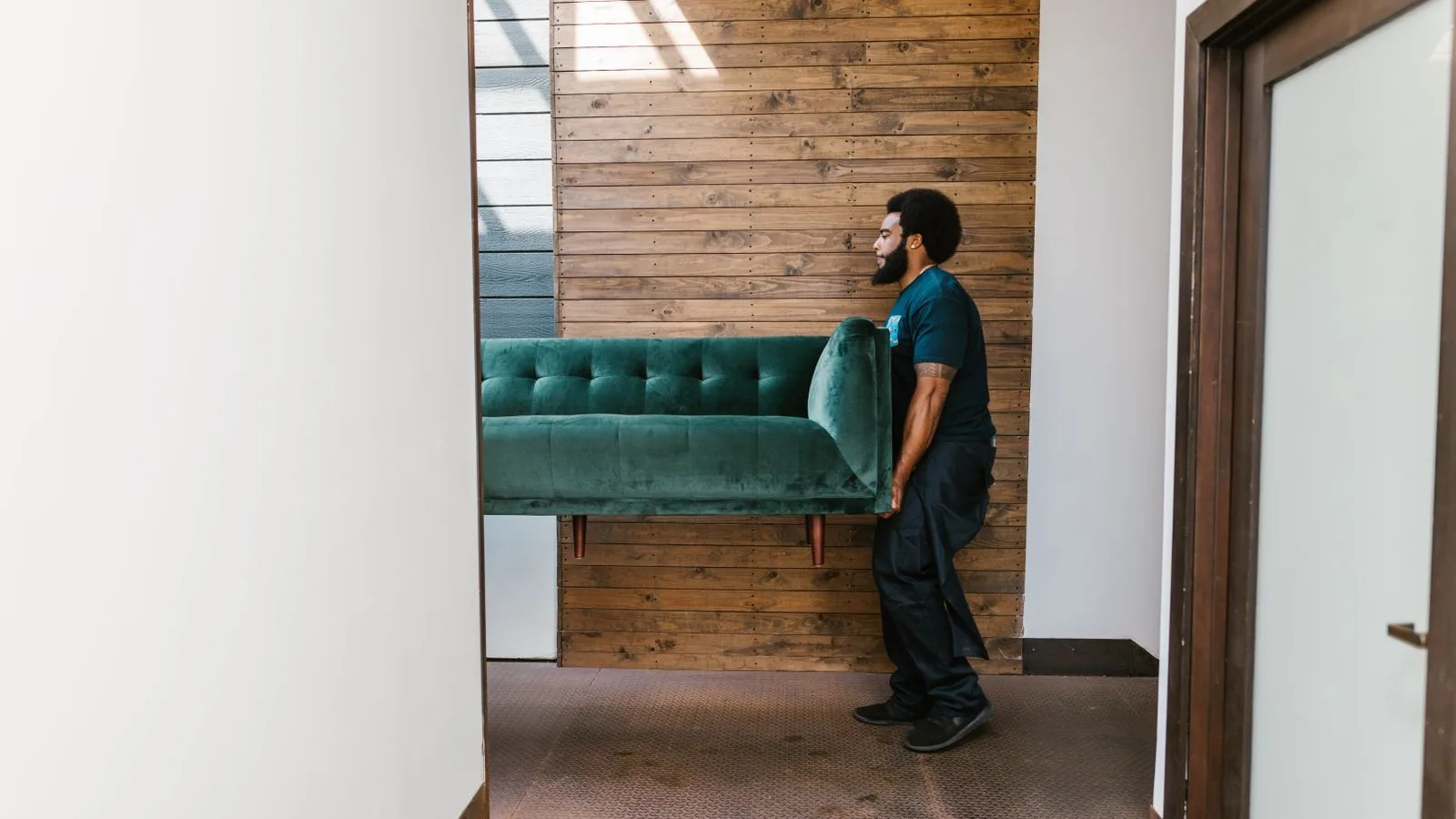 Professional junk pickup crew member in Dubai carrying an old sofa out of a home for collection