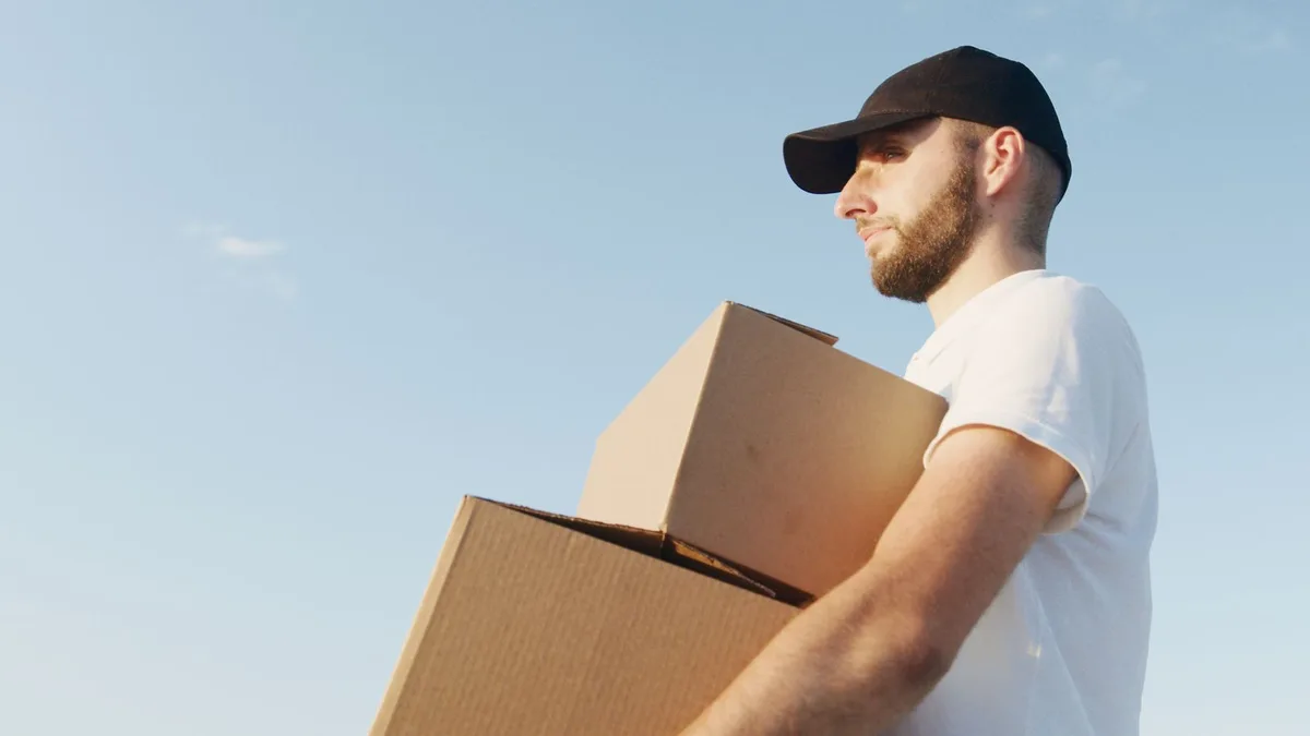 Local crew member carrying boxes out to a waiting vehicle for a same-day junk removal in Dubai