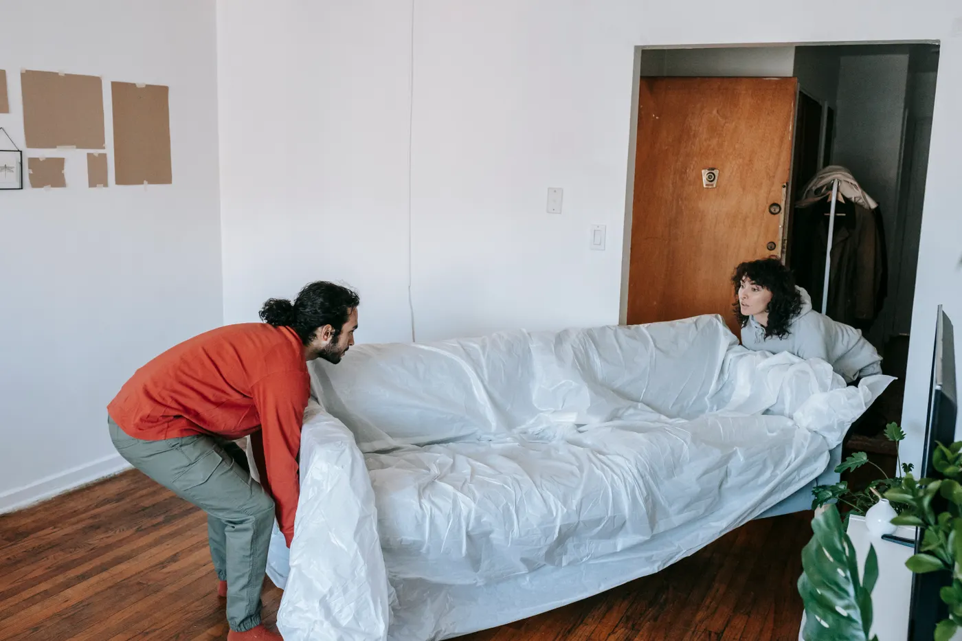 Two people lifting a sofa together in an apartment, illustrating the labour included in a junk removal collection in Dubai