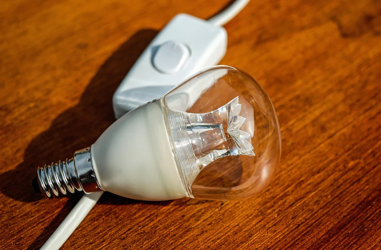 Modern energy-saving LED light bulb with clear glass dome and screw fitting resting on a polished wooden surface