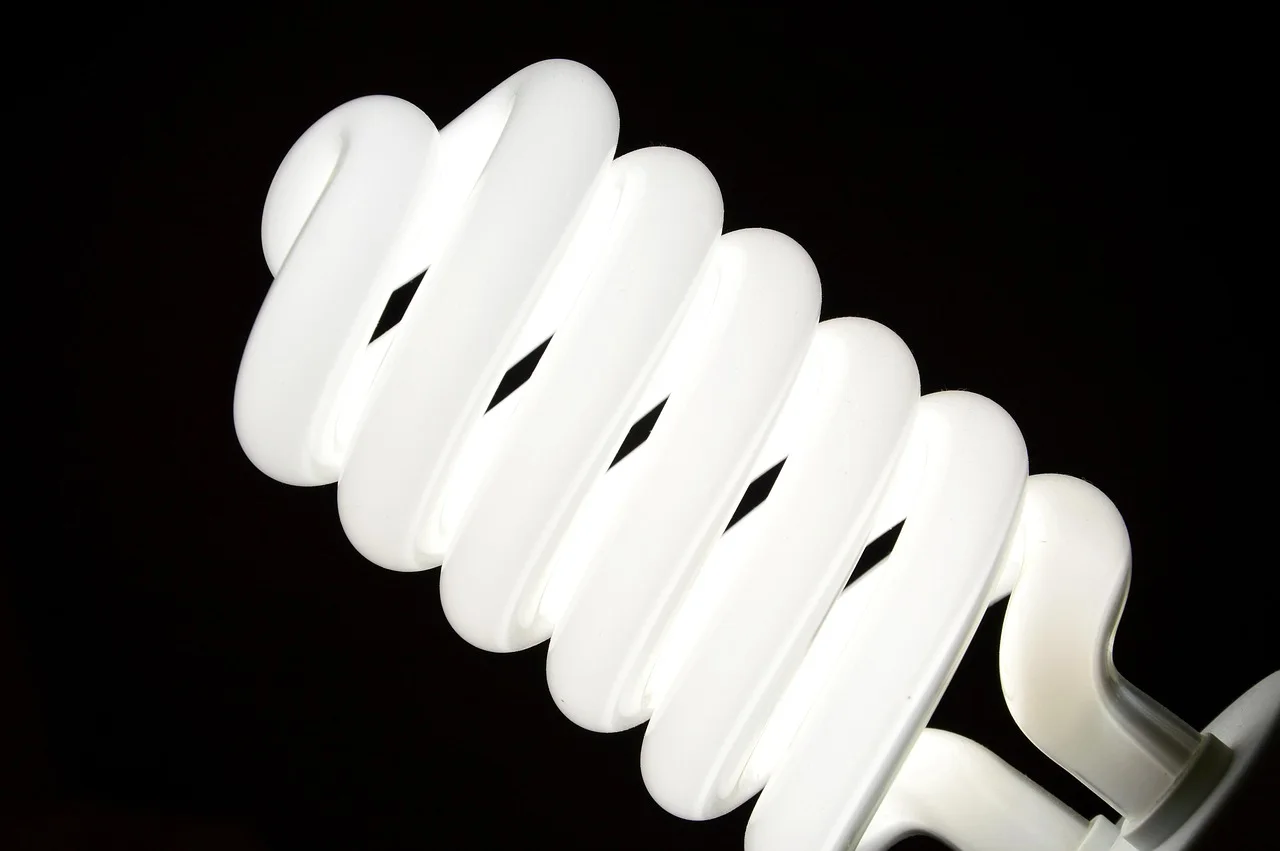 Spiral compact fluorescent light bulb showing white phosphor-coated coiled glass tubing against a dark background