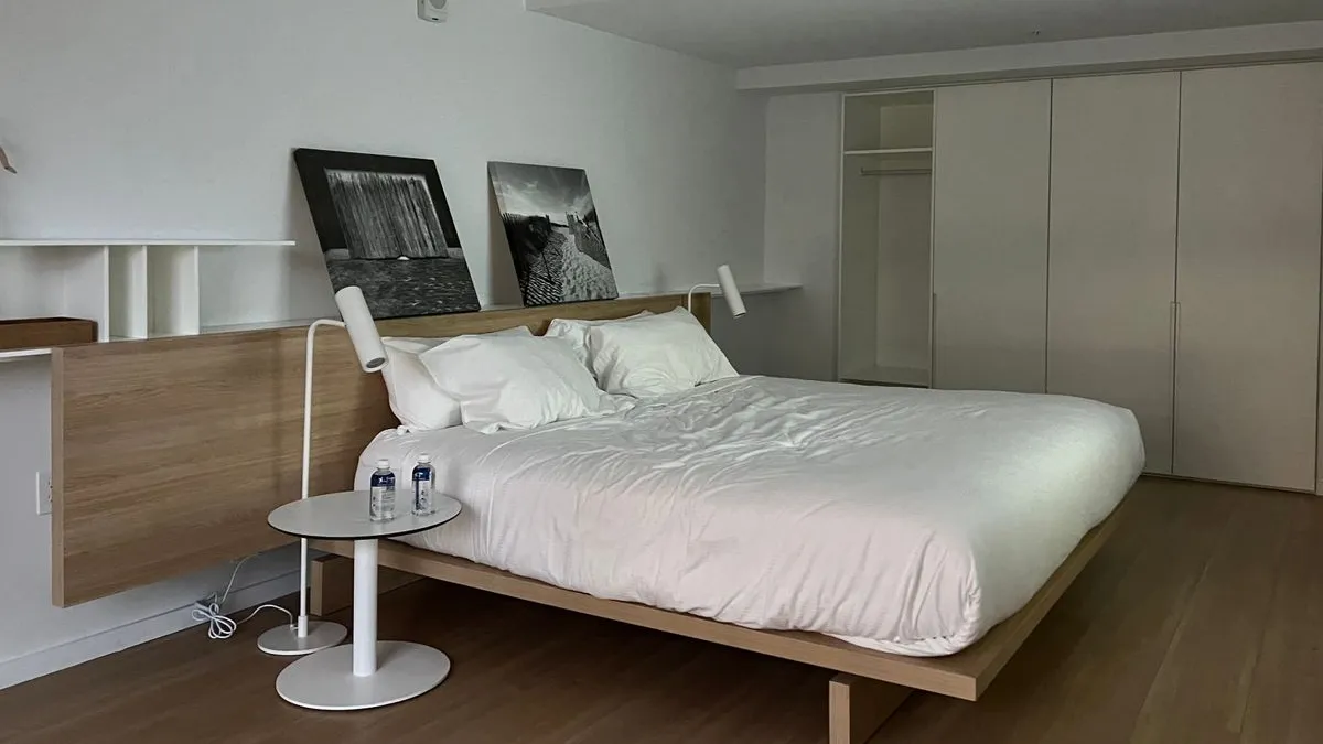 Made double bed on a platform base in a minimalist Dubai hotel room ahead of a batch mattress pickup