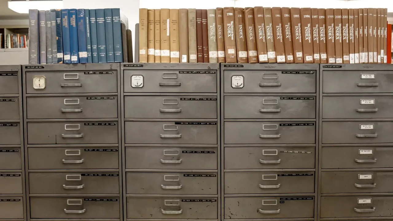 Rows of labelled steel office filing drawers with reference books stored above