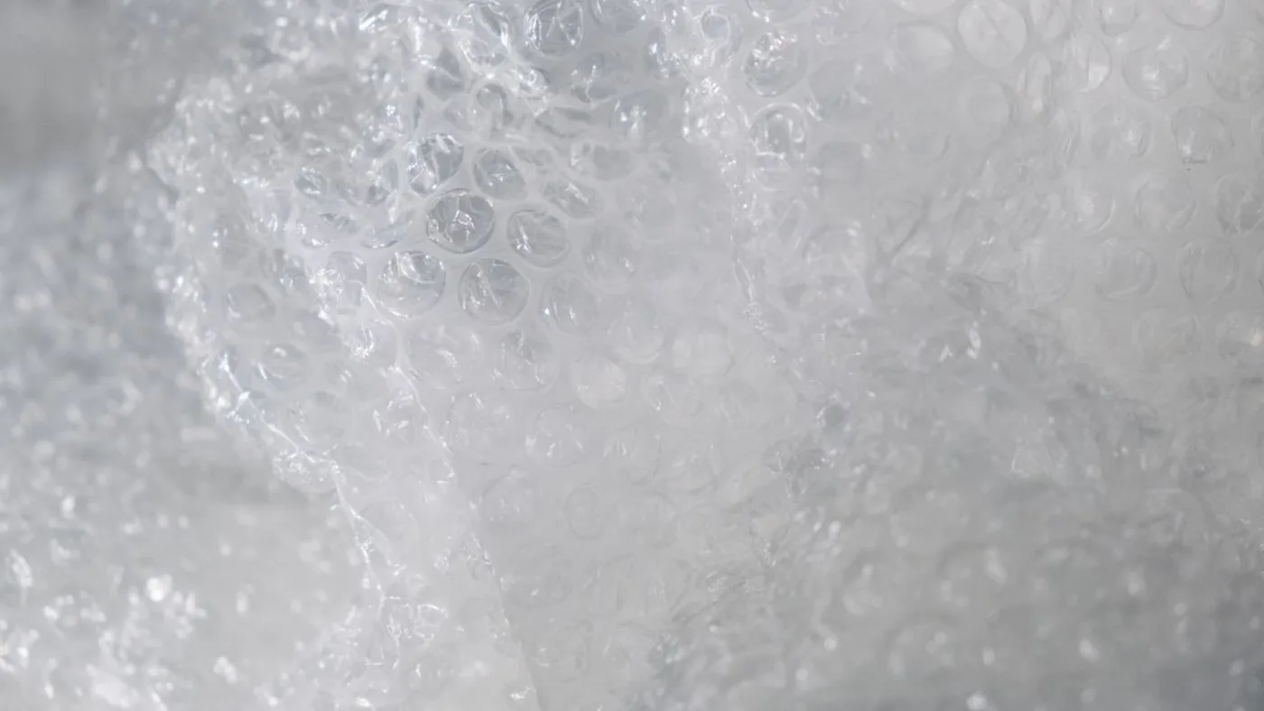 Crumpled sheet of clear plastic bubble wrap filling the frame with light catching the individual bubbles