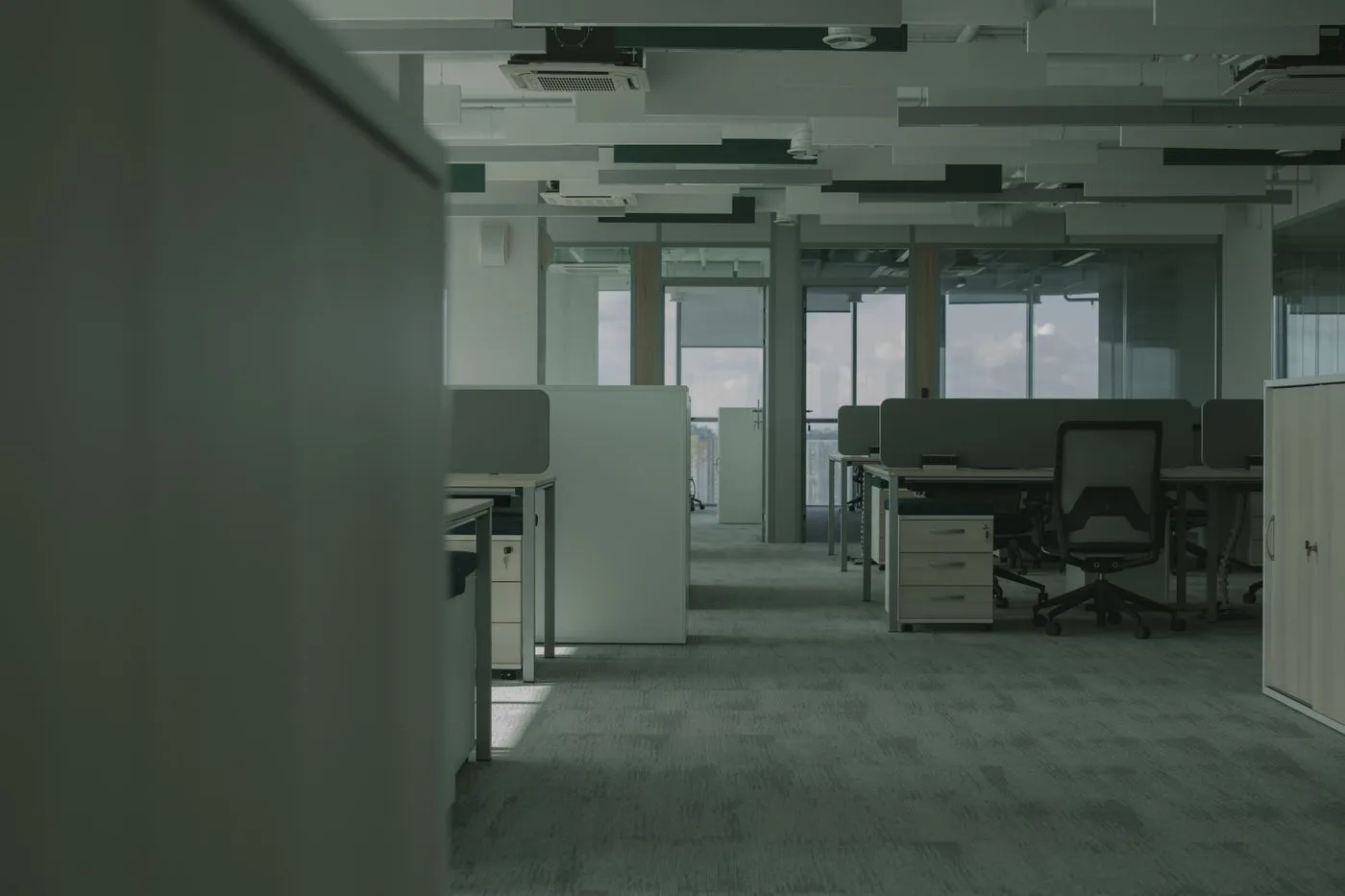 Partly emptied open plan office floor with bench desks, pedestals, desk screens and a single task chair