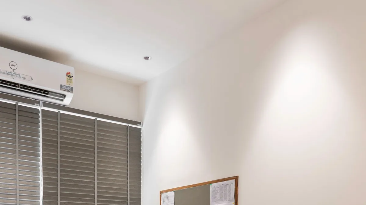 White reception desk counter with wood-panel base and office chairs in a Dubai office lobby prepared for desk removal