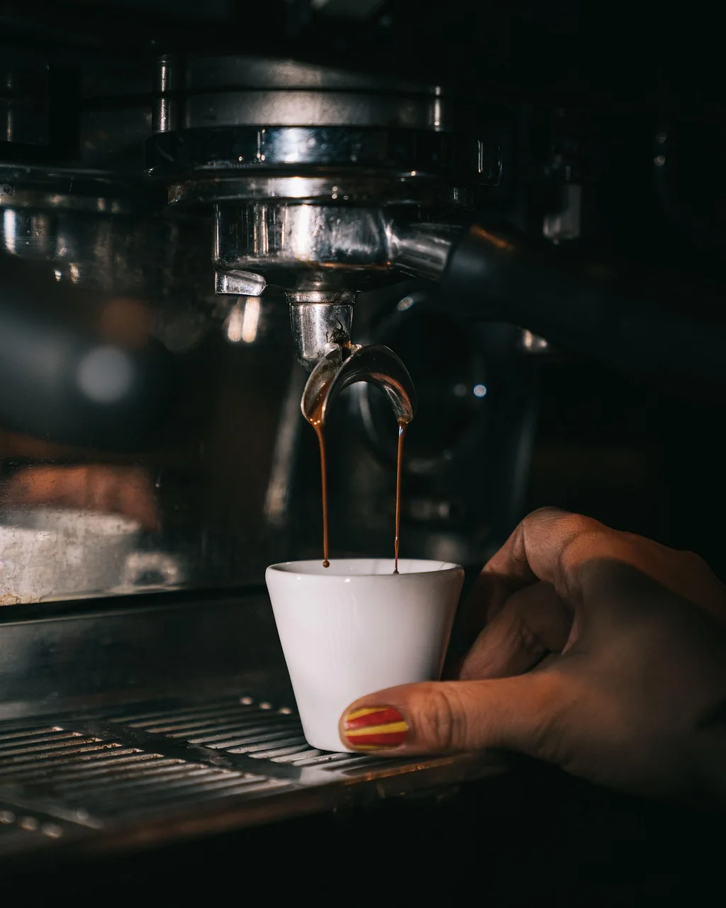 Commercial espresso coffee machine pouring espresso into a white cup in a corporate cafe station