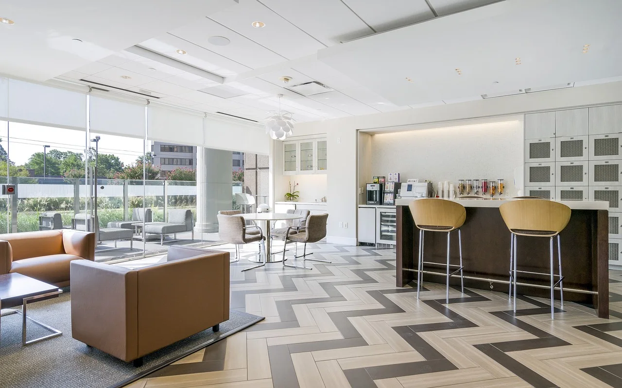 Corporate office cafeteria and pantry breakroom with bar counter, modern high stools, lounge armchairs, and beverage fridges