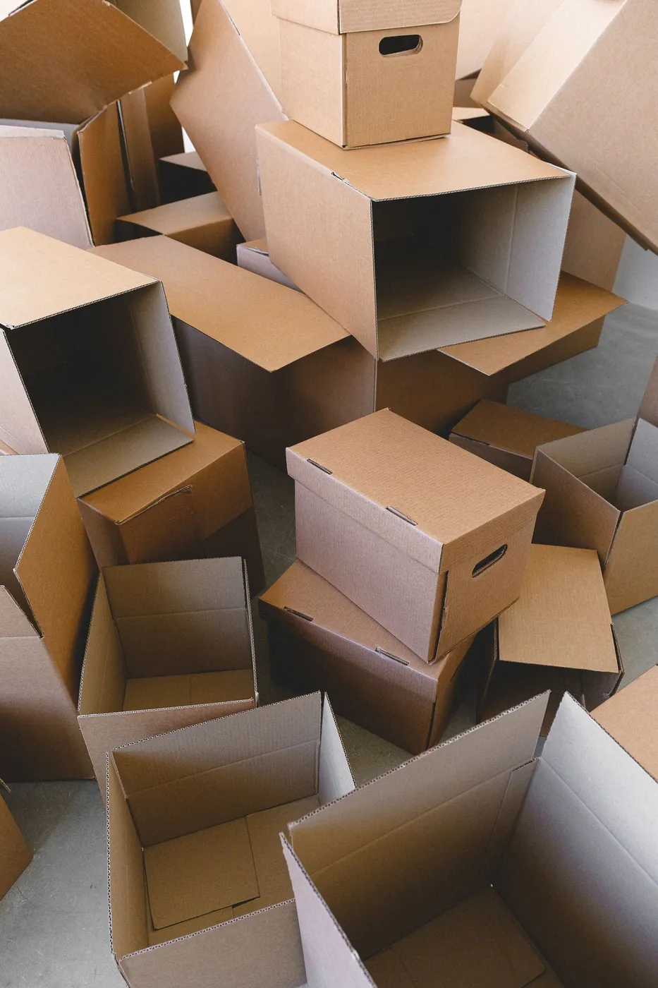Pile of empty cardboard archive and moving cartons with open flaps stacked on a concrete floor