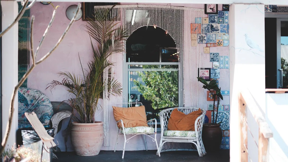 Weathered white wicker and metal outdoor chairs with worn cushions on a shaded porch