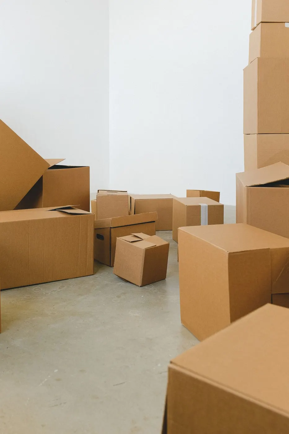 Empty white room with several stacked cardboard boxes of different sizes and no furniture