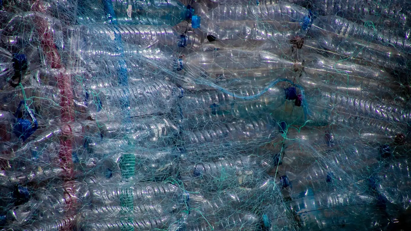 Large industrial bale of clear plastic bottles compressed and wrapped in netting