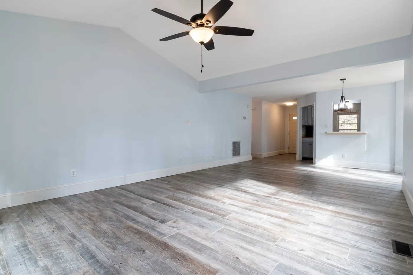 Bright, empty residential living room with wooden flooring and a ceiling fan after a household clear-out in Dubai