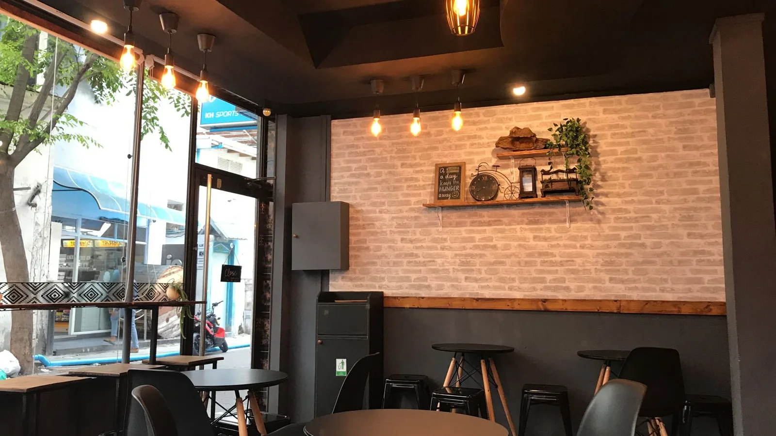 Small retail shop interior in Dubai with tables, stools, wall shelving and a glazed shopfront awaiting retail shop clearance