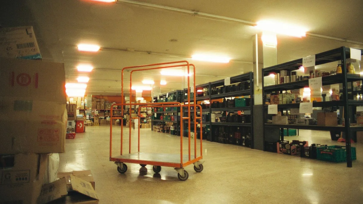 Retail stockroom with metal shelving, stacked boxes and a stock trolley on a polished floor