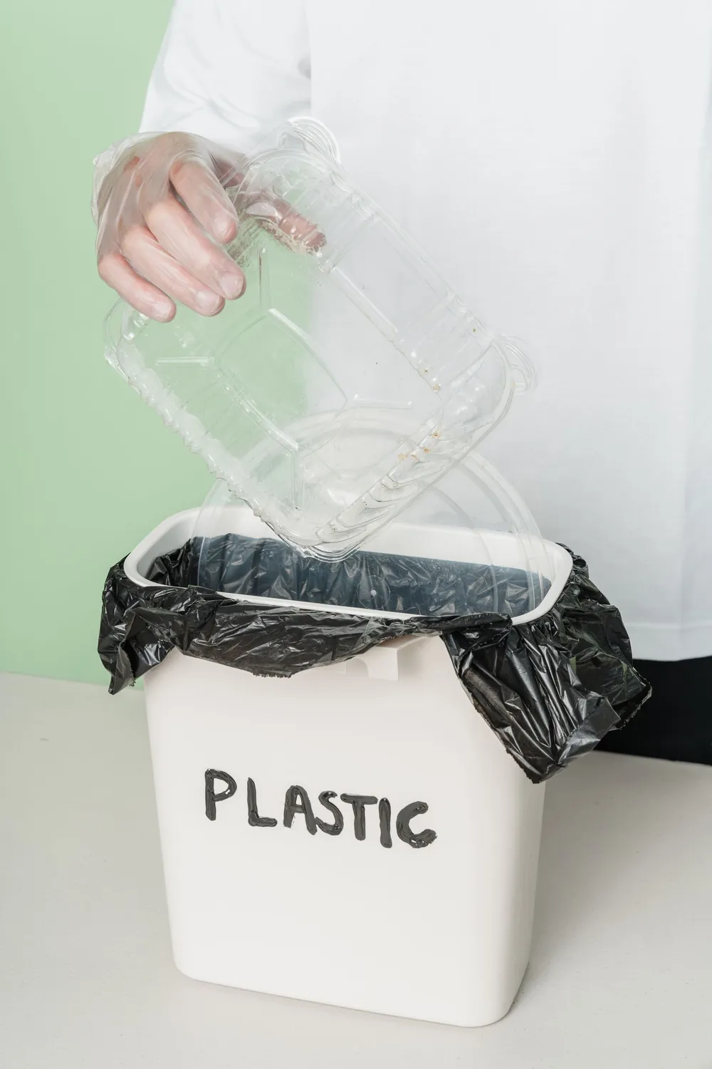 Gloved hand sorting a clean plastic container into a labelled recycling bin during responsible rubbish disposal in Dubai