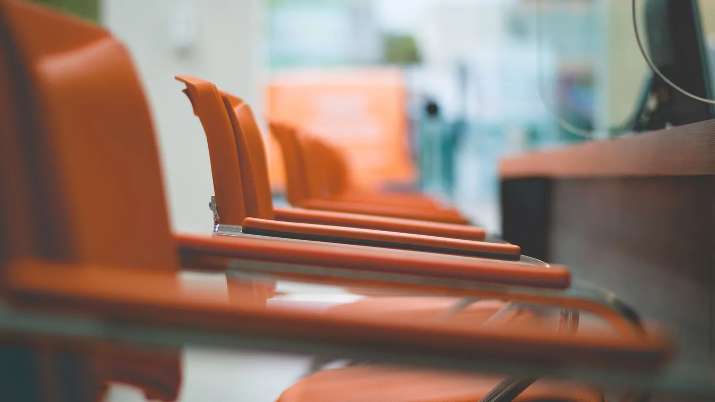 Row of orange leather-upholstered meeting chairs with chrome frames tucked under a glass-topped boardroom table