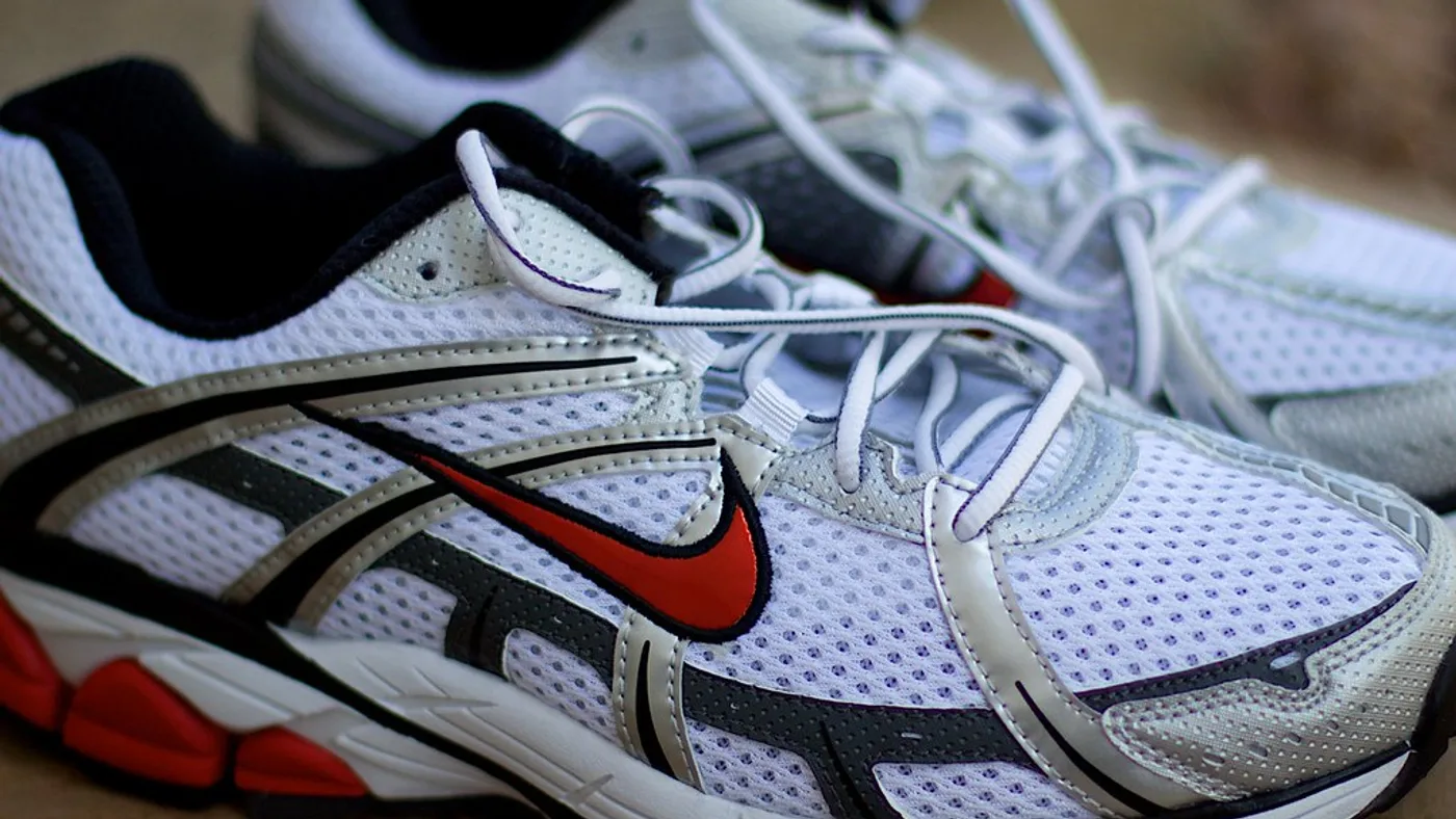 Pairs of sports sneakers tied together by their laces and placed in a cardboard sorting box