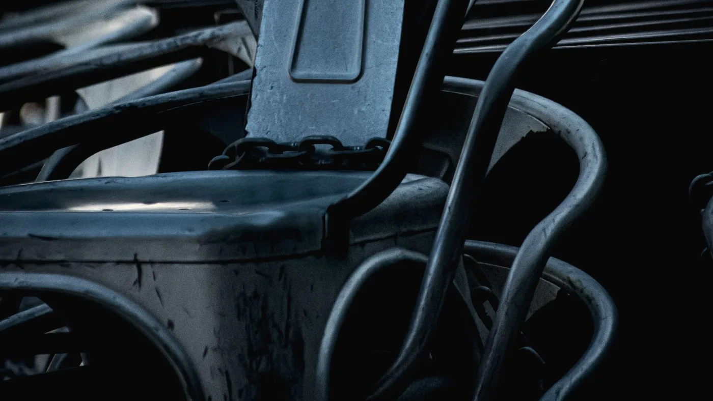Close-up of a stacked chair's tubular metal frame and moulded seat, showing the joints where the backrest connects to the seat