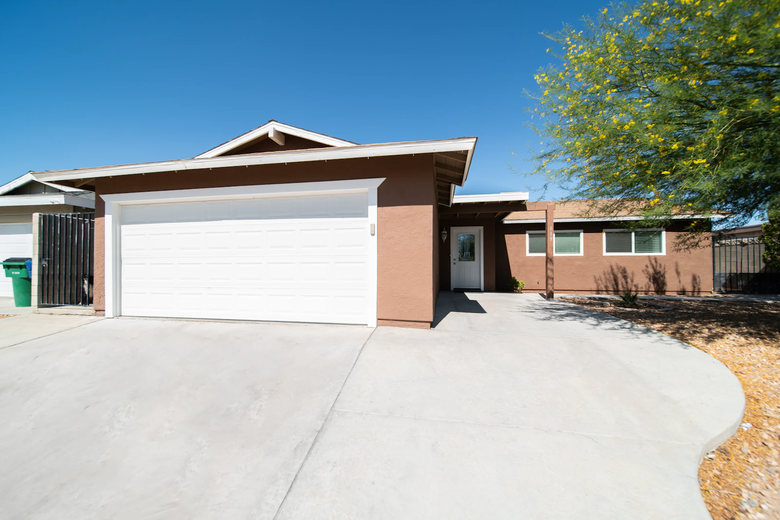 Villa with an attached garage positioned in the middle of a paved driveway